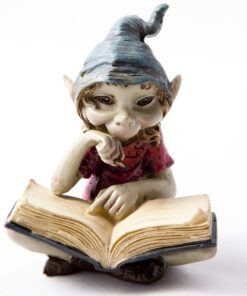 Cornish pesky piskie sitting cross-legged and engrossed in a large book. The pisky has a thoughtful expression, resting its chin on one hand