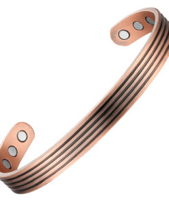 A copper open cuff bangle featuring a series of fine parallel grooves running along its length for a textured, striped effect. The ends are rounded discs inset with large magnets, with additional smaller magnets positioned on the inner surface near each end, combining detailed craftsmanship with potential magnetic therapy benefits.