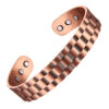 A wide copper open cuff bangle with a distinctive brick-like stepped pattern across its surface, creating a bold and textured appearance. The inside is smooth and fitted with multiple round inset magnets near each end, blending a striking geometric design with potential magnetic therapy benefits.