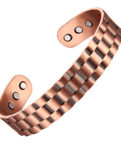 A wide copper open cuff bangle with a distinctive brick-like stepped pattern across its surface, creating a bold and textured appearance. The inside is smooth and fitted with multiple round inset magnets near each end, blending a striking geometric design with potential magnetic therapy benefits.