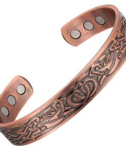A copper open cuff bangle adorned with an intricate engraved Celtic knot and interlaced pattern in a darkened antique finish. The interior is smooth and contains multiple round inset magnets near each end, blending traditional decorative artistry with potential magnetic therapy benefits.