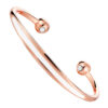 A sleek and polished rose-gold toned open cuff copper bangle with smooth rounded ball ends, each featuring an inset circular magnet for potential healing benefits. The minimalist design has a glossy reflective surface, giving it a modern and elegant look.