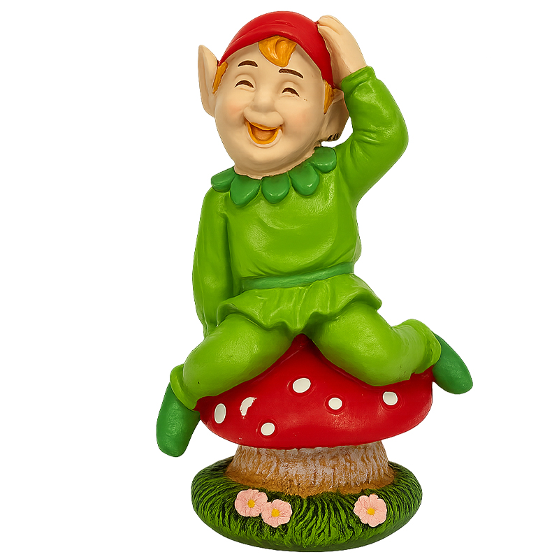 Bright, smiling Cornish pisky figurine in a green outfit with a red hat, sitting on a red spotted mushroom with flowers at the base.