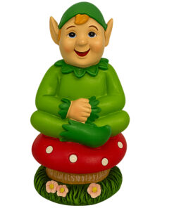 Cheerful Cornish pisky figurine in a green outfit sitting cross‑legged on a red spotted mushroom with flowers at the base.