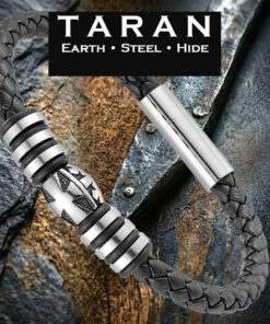 A Taran men's round-braided black leather bracelet featuring a thick woven plait pattern. The centerpiece displays a sculpted silver stainless steel barrel bead carved with a Maltese cross emblem, flanked by alternating polished silver spacer rings and black rubber bands. Includes a high-shine silver magnetic tube clasp