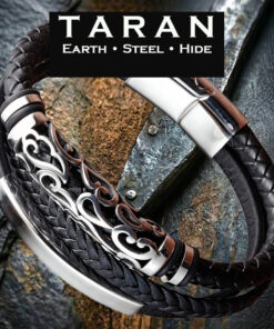 A Taran men's black leather scroll bracelet featuring a multi-strand layout. The design showcases two rows of tightly woven black braided leather alongside a solid round leather foundation cord. An ornate, mirror-polished silver stainless steel tube with deeply carved open-work scroll filigree rests in the center, flanked by a curved silver steel ID bar. The strands lock into a polished geometric magnetic slide clasp.