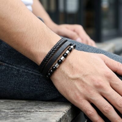 Black multi-strand leather and beaded bracelet with silver accents worn on a man's wrist.