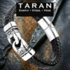 Men's TARAN black braided leather bracelet featuring a carved silver tribal link focal piece and a polished steel magnetic clasp, on a dark slate background.