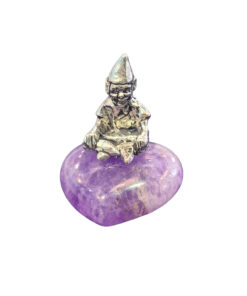 A small pewter Cornish piskey figurine with a pointed hat sitting atop a heart-shaped, vibrant purple amethyst gemstone