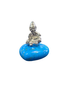 A small pewter Cornish piskey figurine with a pointed hat sitting atop a heart-shaped, vibrant blue turquoise gemstone base.